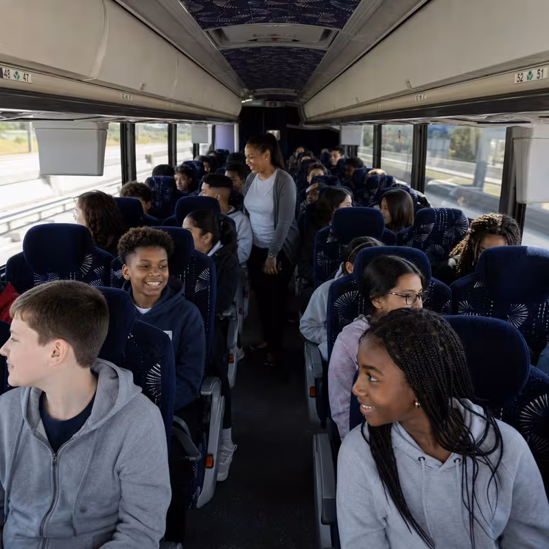 Group boarding a white charter bus for School Transportation transportation in Naperville
